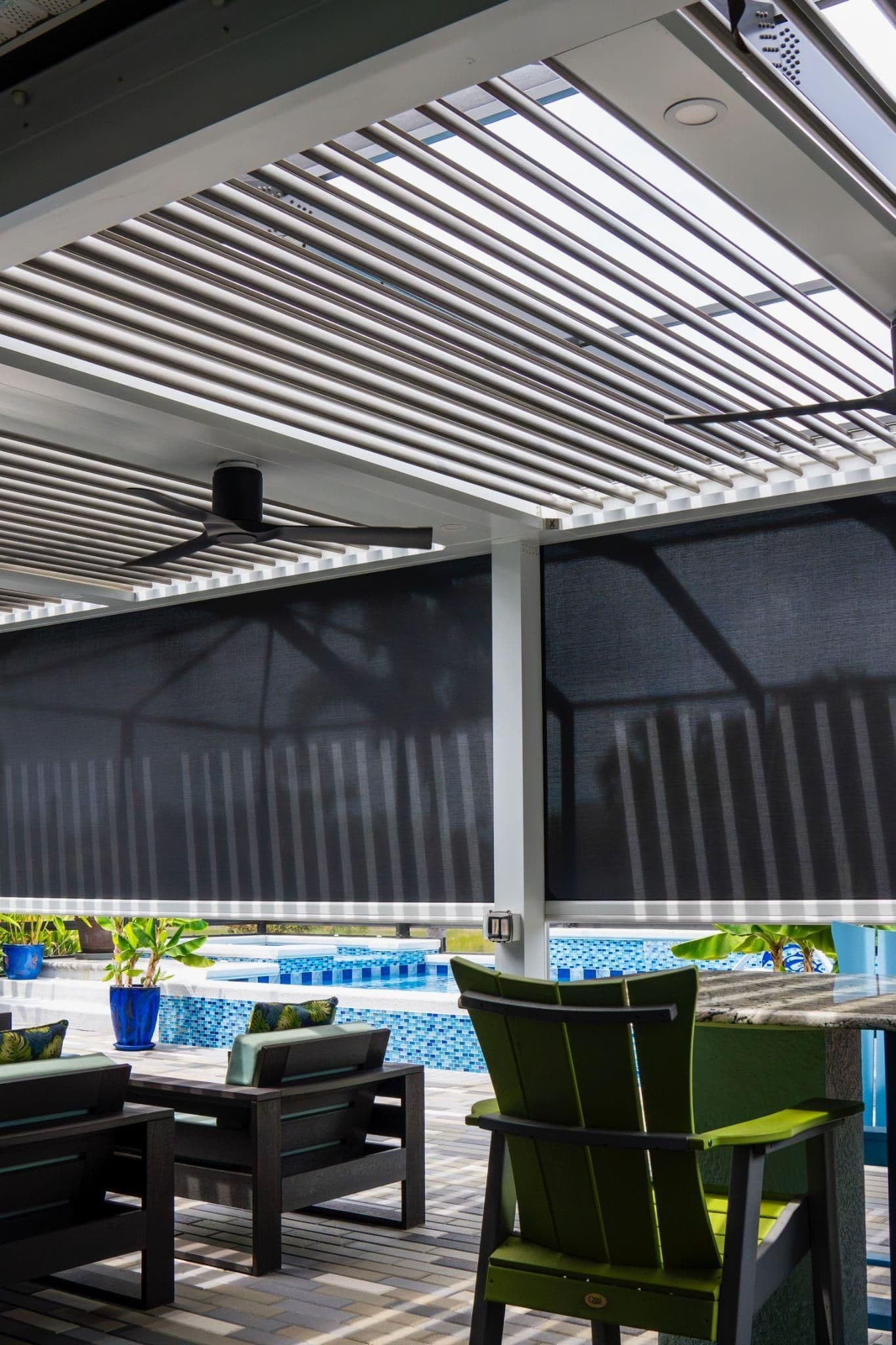 Pool patio with motorized louvered pergola featuring adjustable aluminum slats, ceiling fan, retractable sun shades, and seating area overlooking swimming pool