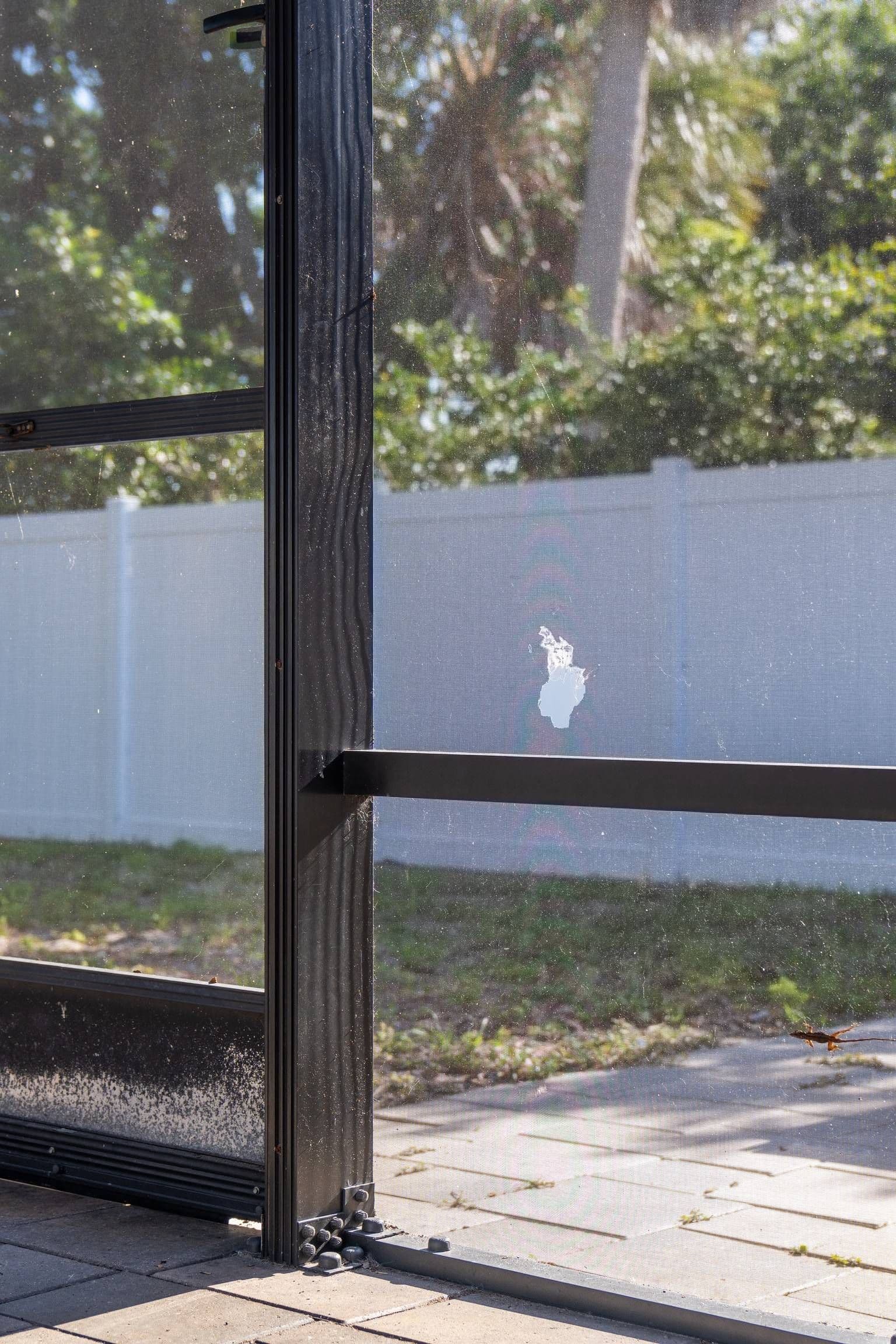 A close-up of a screened-in patio with a hole in the middle panel.