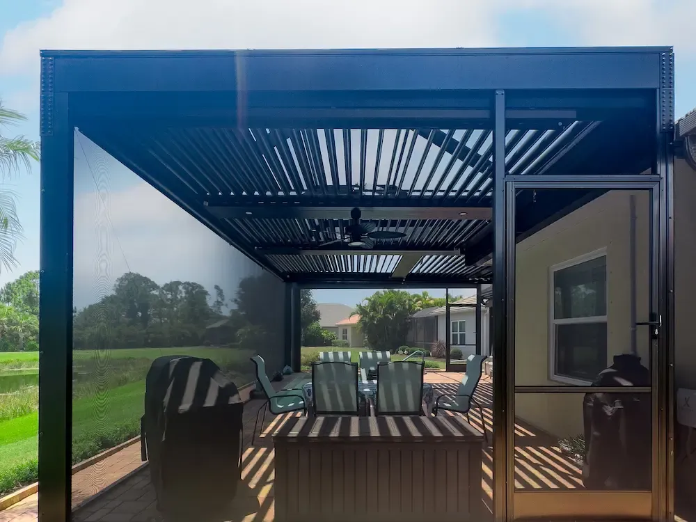 Modern covered patio with a louvered roof, outdoor dining set, grill, and scenic green landscape; striped sunlight creates a relaxed, inviting mood.