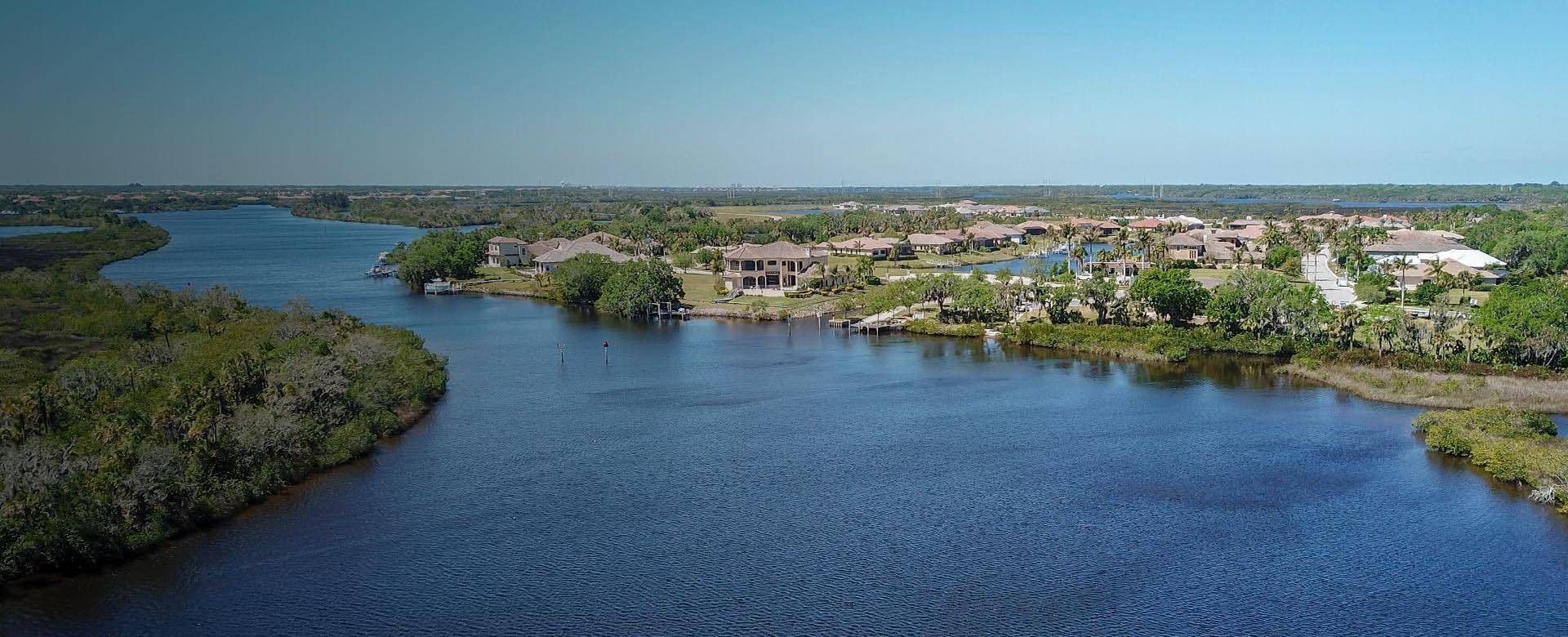 A river flows through a residential area with several houses lining its banks.