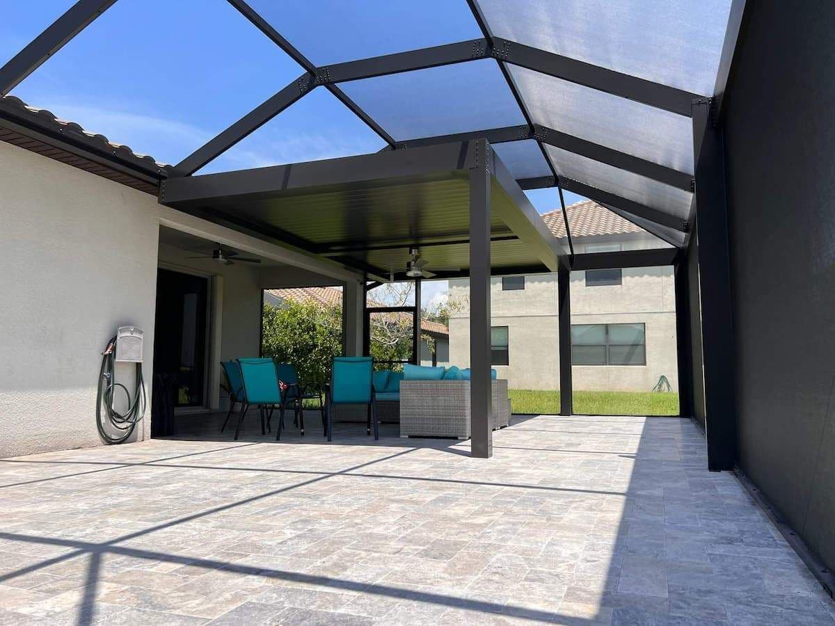 Bright modern patio with covered pergola, turquoise chairs, outdoor table, bicycle, and strong geometric shadows in a sunny courtyard.